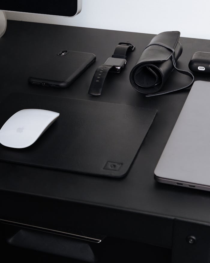 A sleek black workspace featuring modern gadgets like a smartphone, laptop, and digital accessories.